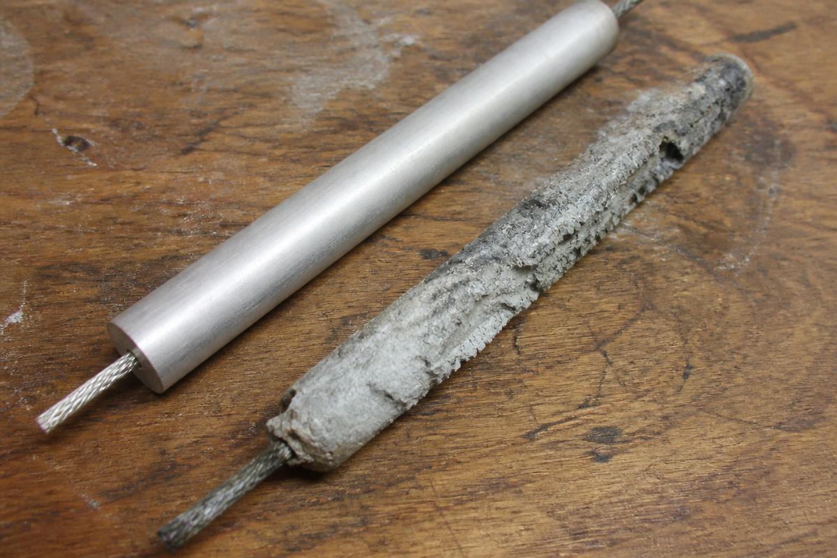 A new sacrificial anode rod beside a heavily corroded one removed from a hot water tank.